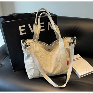 Detail of off-white nylon tote bag with fashion label on a premium leather sofa