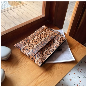 Close-up of leopard print clutch bag with zipper closure on a wooden surface