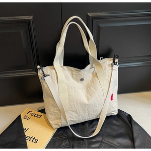 Detail of off-white nylon tote bag with pleated texture and black crossbody strap