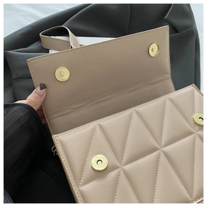 Close-up of beige quilted bag showing triangle stitching and gold magnetic closures