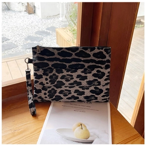 Detail of leopard print clutch bag with wristlet strap and metal zipper closure