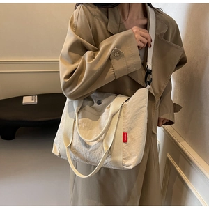 Detail of beige nylon tote bag with red FASHION tag and detachable wide shoulder strap
