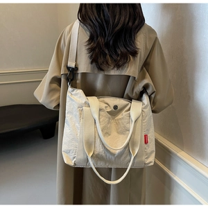 Detailed view of a beige nylon tote bag with fashion label on casual trench coat