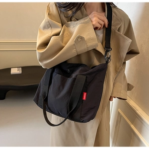 Detail of waterproof black nylon tote bag with fashion tag and durable webbing strap