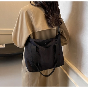 Rear view of a black nylon tote bag showing its large capacity and stylish crossbody strap