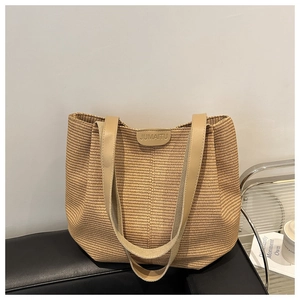 Dettaglio di una grande borsa tote intrecciata beige con spalline in pelle e logo