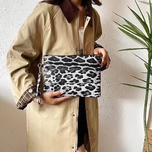 Chic leopard print clutch bag with detachable strap shown with elegant trench coat