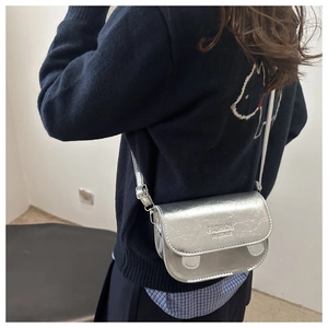 Detail of silver metallic crossbody bag with textured leather and fashion lettering