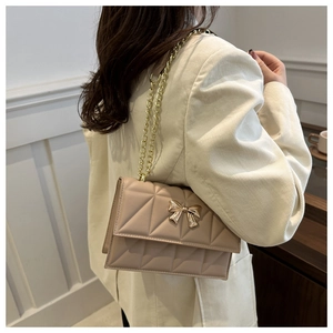 Chic quilted flap bag in apricot finish featuring gold chain and bow buckle on model