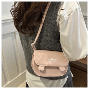 Pink minimalist crossbody bag with cat ear detail worn by a model in casual knitwear
