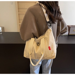 Detail view of large nylon tote bag with red fashion label on shoulder of model