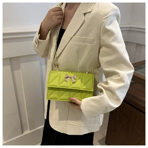 Detailed macro view of fluorescent green quilted square bag with gold bow clasp