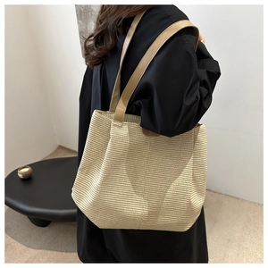 Dettaglio della borsa tote intrecciata beige con trama fine e manici in pelle marrone