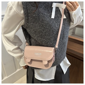 Detail of pink glossy crossbody square bag with Fashion In Stance text and sleek strap
