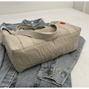 Close-up of durable nylon tote bag with wide strap and red fashion label detail