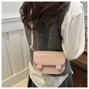Detail shot of a pink leather crossbody bag showing fashion letter print and texture