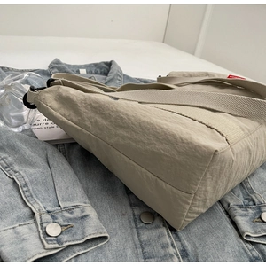 Detailed view of beige crinkled nylon fabric and Fashion tag on large tote bag