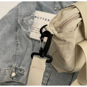 Detail of nylon bag showing black swivel hook, beige wide strap and smooth metal zipper