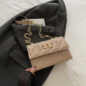 Beige quilted crossbody bag with gold bow ornament and elegant chain strap for women