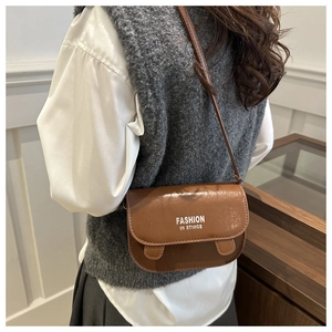 Brown polished faux leather shoulder bag featuring a white slogan print and flap design