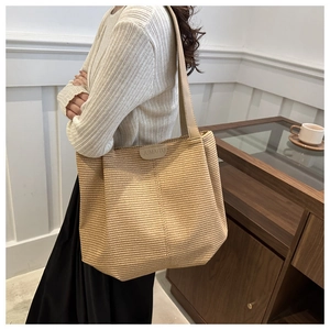 Dettaglio della borsa tote beige a pieghe con etichetta JUMAITU e tracolla larga