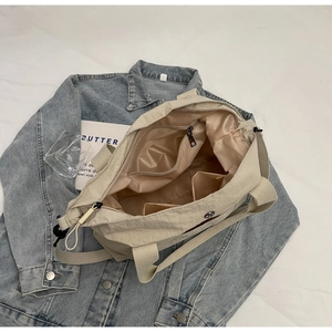 Top-down view of beige nylon tote bag interior showing zip pocket and lining details