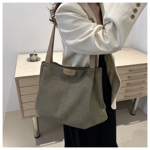 Dettaglio della trama intrecciata e dei manici in pelle marrone della borsa tote capiente