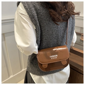 Detail shot of brown PU leather crossbody bag with white fashion slogan print and shoulder strap
