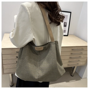 Dettaglio macro della borsa tote intrecciata con tracolla in pelle sulla spalla della modella