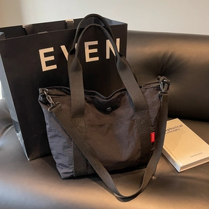 Large black nylon tote bag with fashion label on a leather sofa minimalist setting