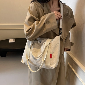 Large beige nylon tote bag with adjustable shoulder strap and fashion label for women