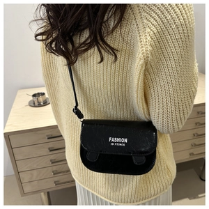 Close-up of a black glossy PU leather crossbody bag featuring white printed text detail