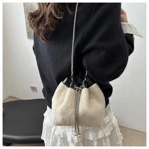Detalle de bolso tipo cubo de felpa beige con cadena y perlas en el cordón