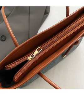 Macro detail of the smooth metal zipper and leather piping on the grey tote bag