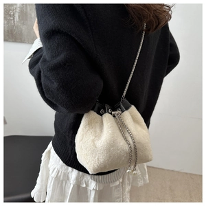 Detalle de bolso tipo cubo de felpa blanco roto con cadena plateada y detalles de perlas