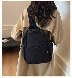 Détail d'un sac à dos en nylon noir avec étiquette de marque et cordon de serrage réglable