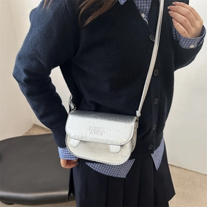 Silver metallic crossbody bag with cracked texture and lettering on the flap