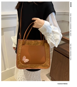 Detailed view of brown PU leather tote bag with fur trim and pink butterfly embroidery