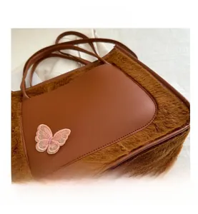 Close-up of brown PU leather bag with dark faux fur trim and pink butterfly embroidery