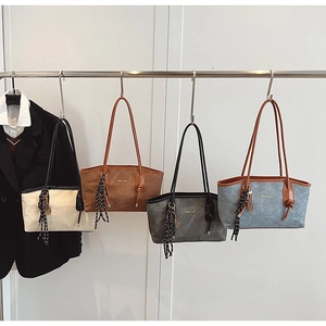 Row of four large leather tote bags in cream, brown, grey and blue on a metal hanger