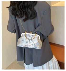 Detailed view of embroidery flower patterns on a vintage clasp bag with golden chain strap