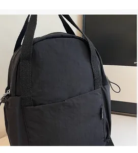 Détail d'un sac à dos noir en nylon montrant sa texture plissée et sa poche de rangement