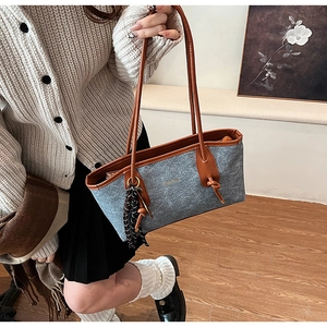 Detail of grey felt tote bag with brown leather straps and gold branding text