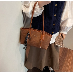 Detail of a brown textured leather tote bag with silk scarf and gold lettering