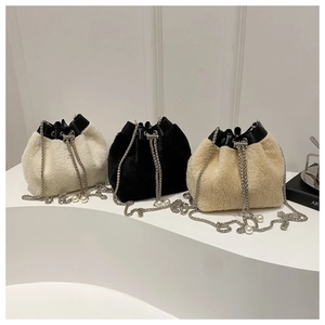 Detalle de bolsos tipo cubo de peluche en blanco, negro y beige con cordón de perlas
