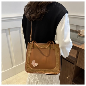 Detailed view of brown PU leather tote with plush trim and embroidered butterfly