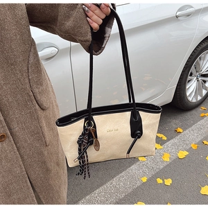 Detail view of large tote bag with contrast piping and tennis racket charm accessory