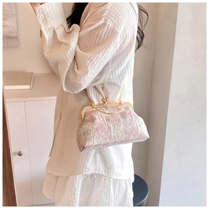 Detailed macro view of pink floral jacquard fabric and golden heart-shaped clasp on retro bag