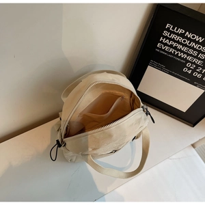 Vue intérieure du mini sac à dos en nylon blanc cassé montrant la poche zippée interne