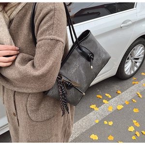 Detail of grey PU leather tote bag with silk scarf charm and drawstring in street style